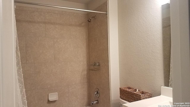 bathroom with shower / bath combo with shower curtain, vanity, and a textured wall