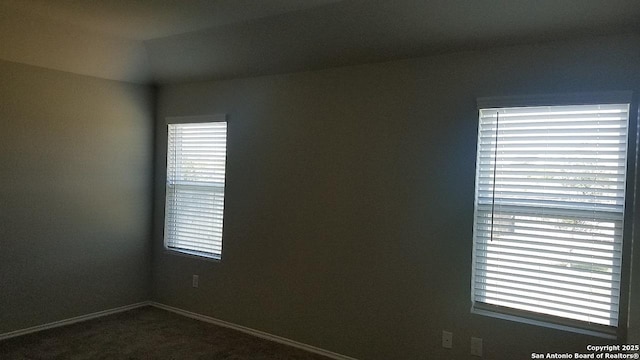 unfurnished room with baseboards and dark carpet