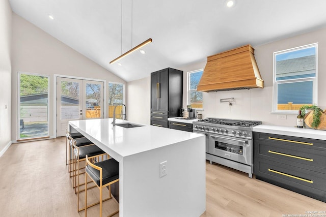 kitchen with premium range hood, a breakfast bar, high end stainless steel range, a sink, and light countertops