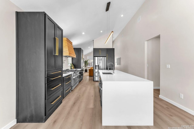 kitchen featuring a sink, light wood-type flooring, light countertops, stainless steel appliances, and a kitchen island with sink