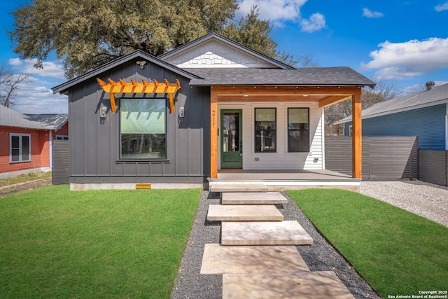 view of front of property featuring a porch, board and batten siding, a shingled roof, and a front lawn