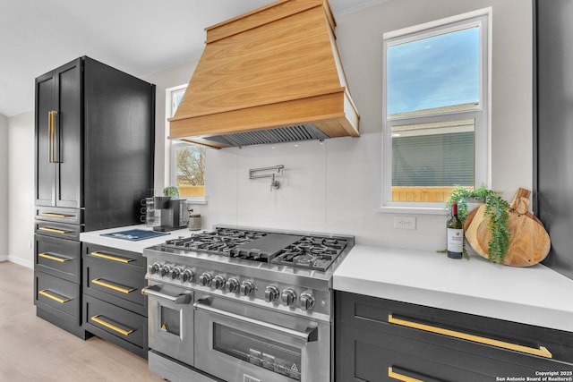 kitchen with double oven range, light countertops, dark cabinetry, light wood-style floors, and custom exhaust hood