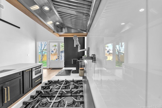 kitchen featuring visible vents, stainless steel gas cooktop, light countertops, light wood-style flooring, and dark cabinetry