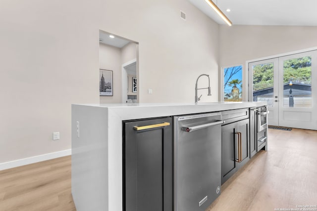 kitchen featuring light countertops, light wood-style flooring, baseboards, and stainless steel appliances