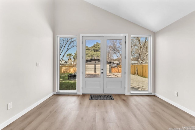 doorway to outside with french doors, lofted ceiling, baseboards, and wood finished floors