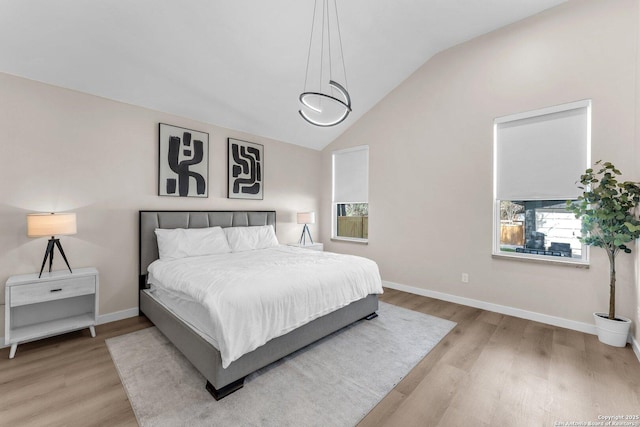 bedroom featuring wood finished floors, baseboards, and vaulted ceiling