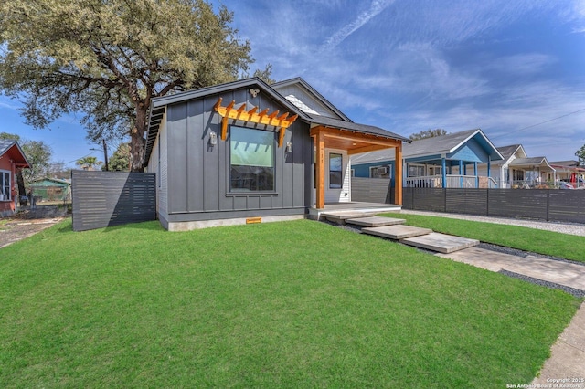 view of front of house with crawl space, board and batten siding, a front yard, and fence