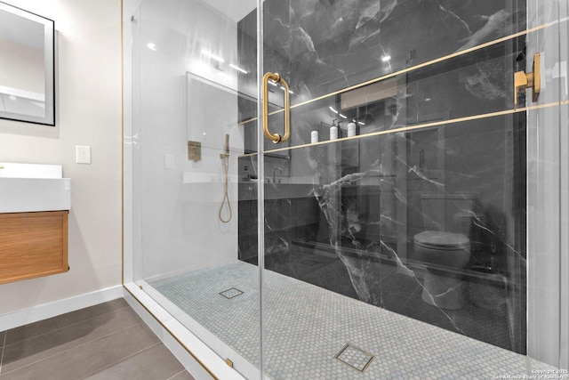 bathroom featuring a stall shower, toilet, vanity, and baseboards