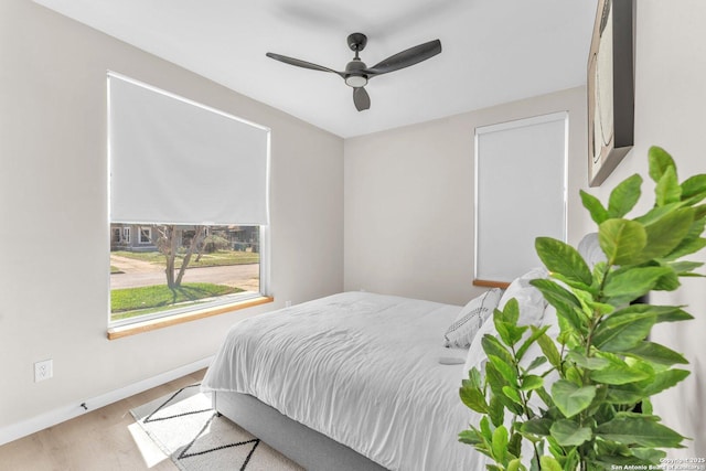 bedroom with ceiling fan, baseboards, and wood finished floors