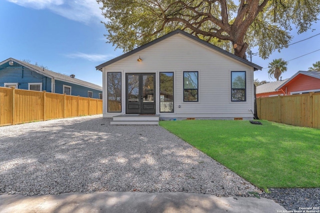 rear view of property with crawl space, a yard, a fenced backyard, and french doors