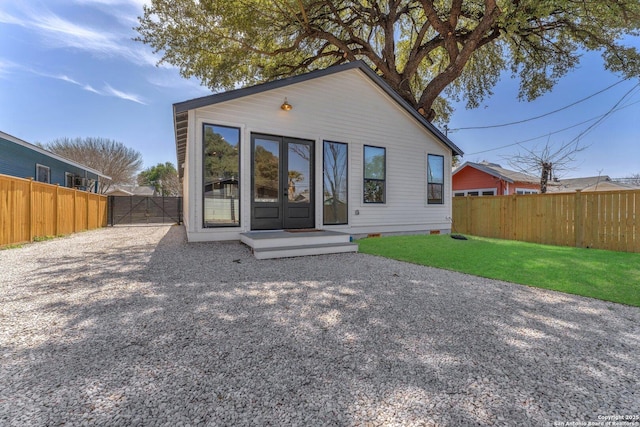 back of property with a gate, a lawn, driveway, and fence