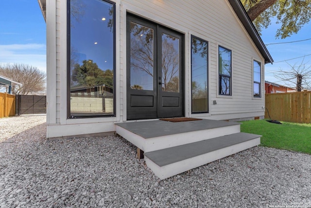 entrance to property featuring a gate, french doors, and fence