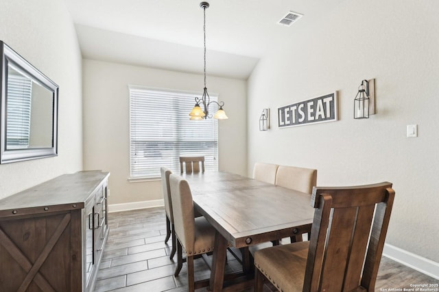 dining room featuring light wood-type flooring, visible vents, baseboards, and a notable chandelier