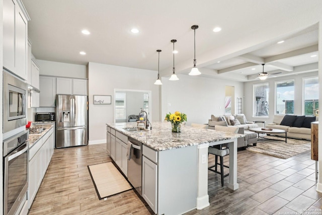 kitchen with light wood-style flooring, recessed lighting, a sink, stainless steel appliances, and a kitchen bar