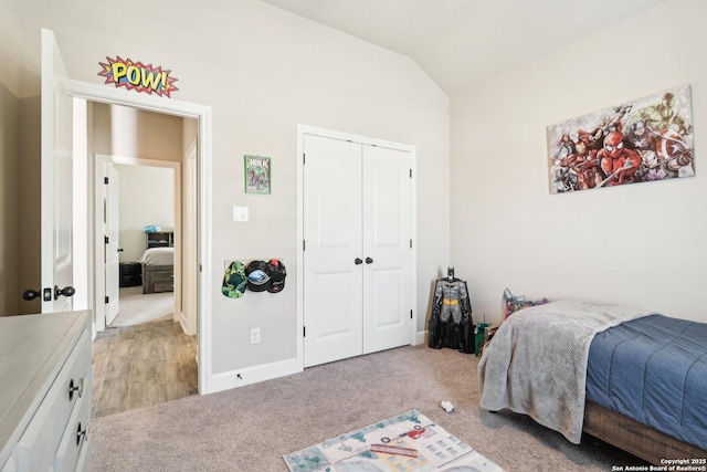 bedroom featuring lofted ceiling, baseboards, a closet, and light carpet