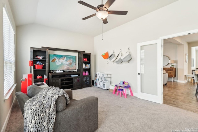 carpeted living area featuring french doors, baseboards, lofted ceiling, and ceiling fan