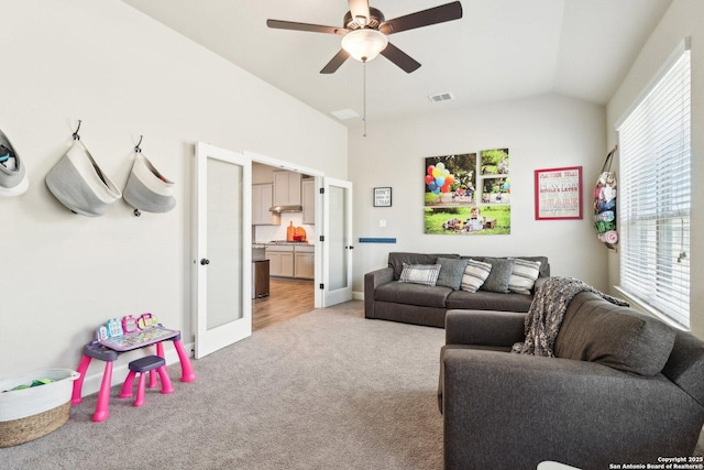 living area with a ceiling fan, visible vents, lofted ceiling, french doors, and light colored carpet