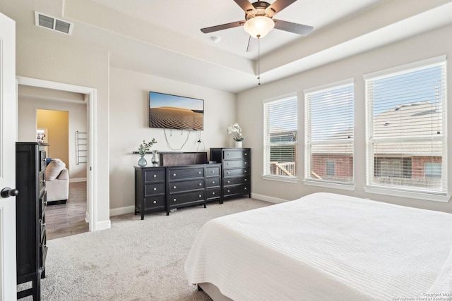 bedroom with baseboards, visible vents, carpet floors, ceiling fan, and a raised ceiling