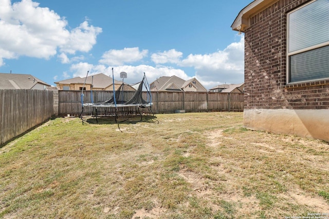 view of yard with a trampoline and a fenced backyard