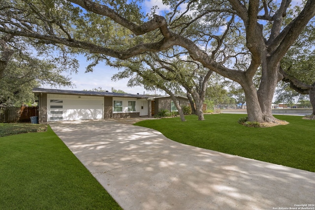 view of front facade featuring driveway, a front lawn, an attached garage, and fence