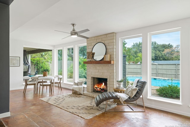 living room with baseboards, ceiling fan, and a fireplace