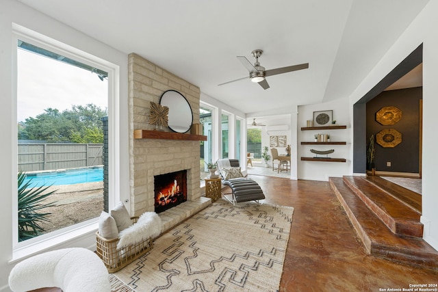 living room with a ceiling fan, a fireplace, baseboards, and concrete floors