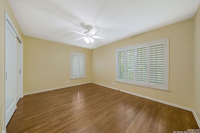 unfurnished bedroom with a closet, a ceiling fan, baseboards, and wood finished floors