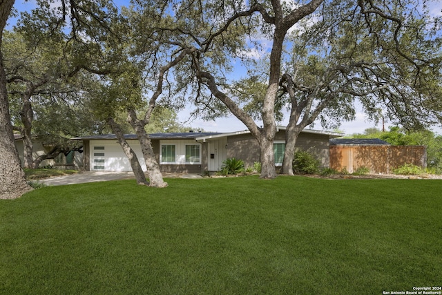 view of front of home featuring a front yard, concrete driveway, fence, and a garage