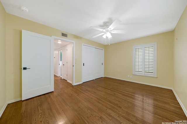 unfurnished bedroom featuring a closet, visible vents, baseboards, and wood finished floors