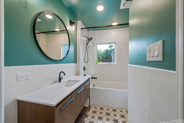 bathroom with tub / shower combination, tile walls, wainscoting, and vanity