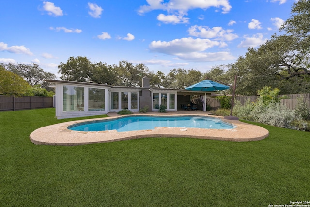 view of swimming pool with a lawn, a fenced backyard, and a fenced in pool