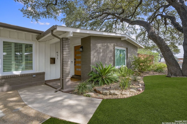 doorway to property featuring a lawn and board and batten siding