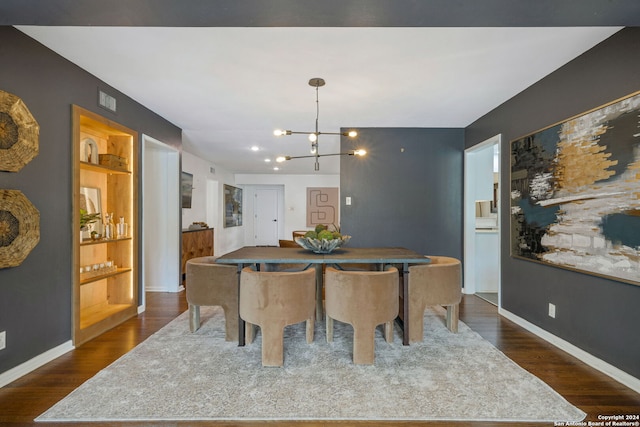 dining space with dark wood finished floors, built in shelves, baseboards, and an inviting chandelier