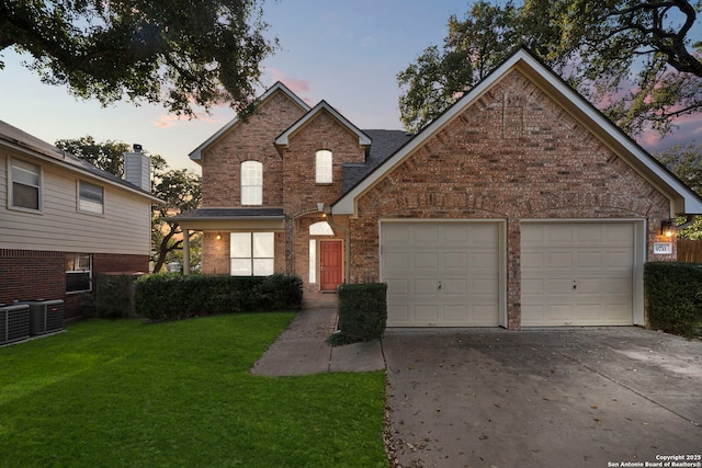 traditional-style home featuring brick siding, concrete driveway, cooling unit, a yard, and an attached garage