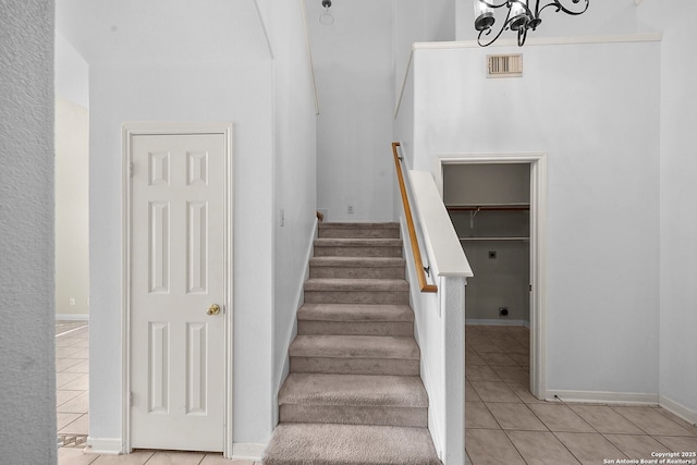 stairway with tile patterned flooring, a notable chandelier, baseboards, and visible vents