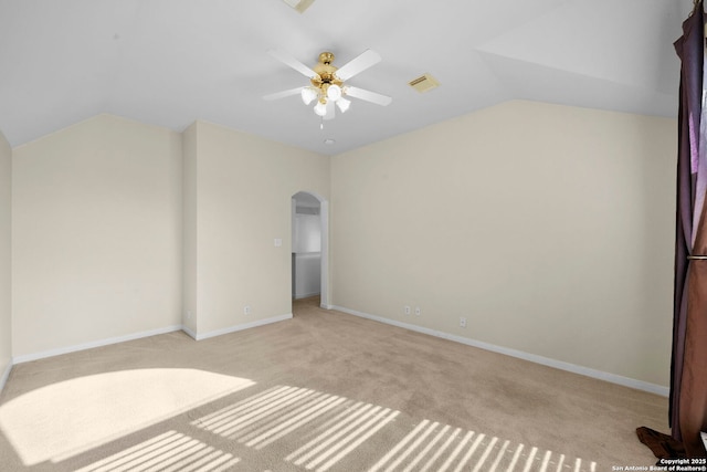 unfurnished bedroom with visible vents, light carpet, arched walkways, baseboards, and vaulted ceiling