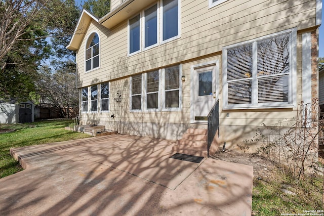 back of house featuring a patio, a yard, entry steps, an outdoor structure, and a storage shed