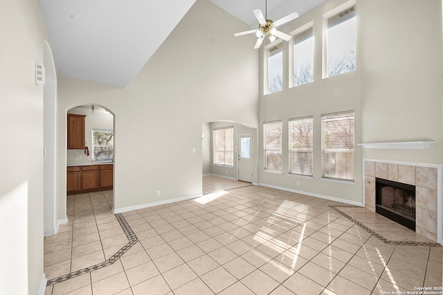 unfurnished living room featuring arched walkways, a ceiling fan, and baseboards