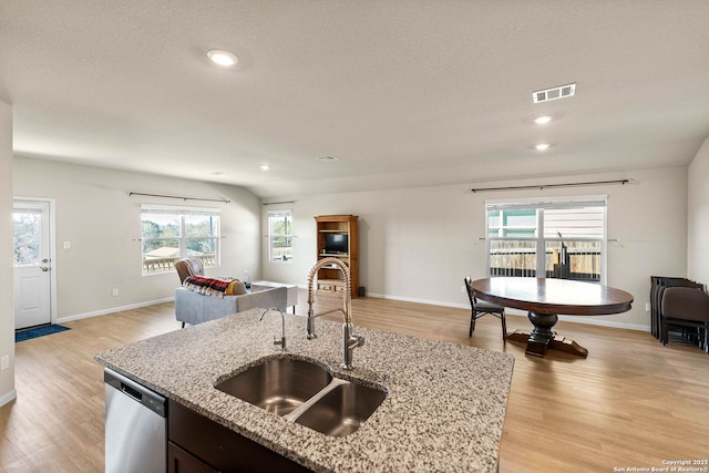 kitchen with visible vents, light wood-style flooring, a sink, stainless steel dishwasher, and open floor plan