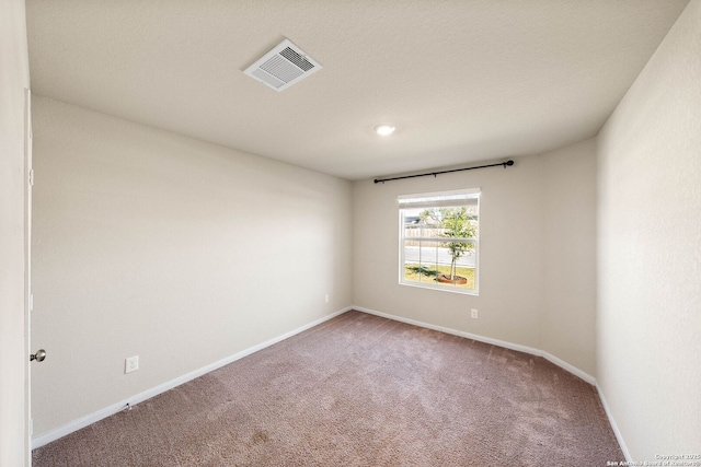 carpeted empty room featuring visible vents and baseboards