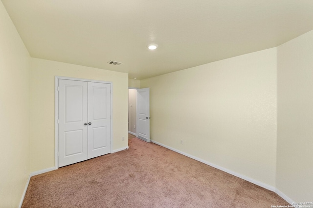 unfurnished bedroom featuring visible vents, light carpet, baseboards, and a closet