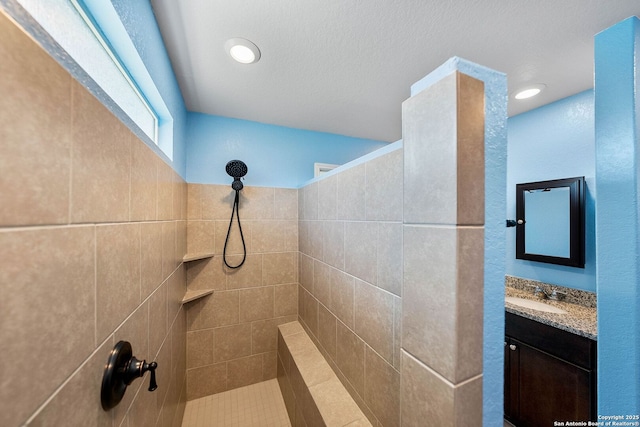 bathroom featuring recessed lighting, tiled shower, and vanity