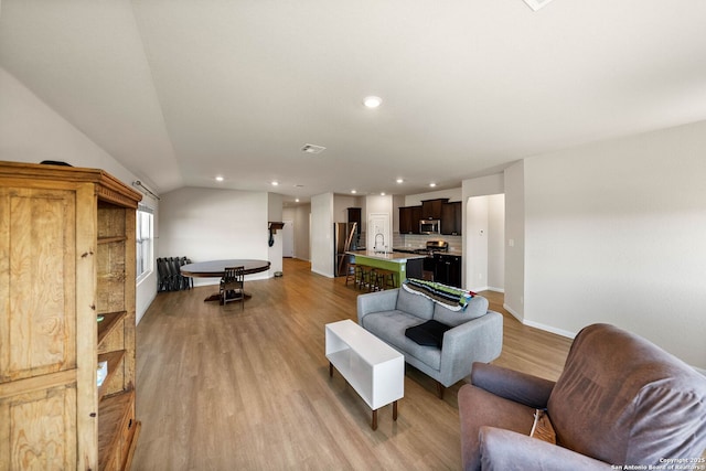 living area featuring visible vents, baseboards, lofted ceiling, recessed lighting, and light wood-style floors