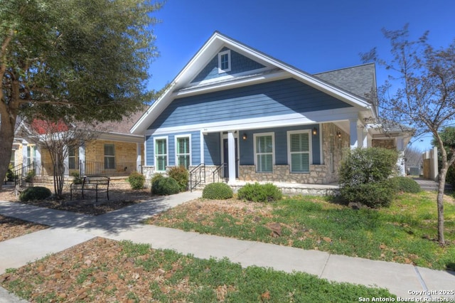 bungalow-style home featuring a porch and stone siding