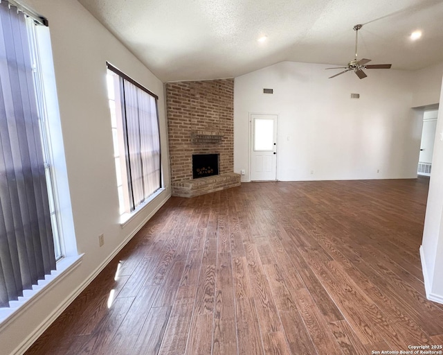 unfurnished living room with wood finished floors, lofted ceiling, ceiling fan, and a fireplace