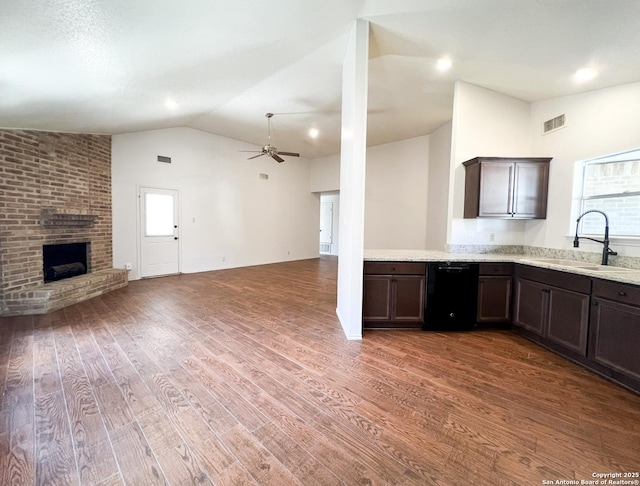 kitchen with wood finished floors, visible vents, lofted ceiling, a fireplace, and a sink