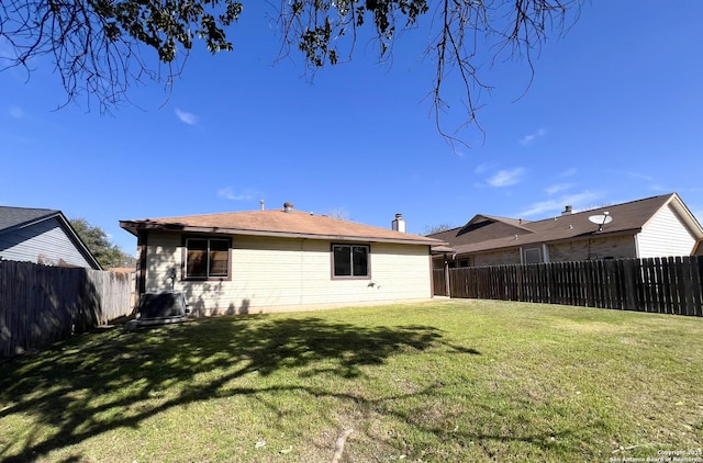 rear view of property featuring central AC, a lawn, and a fenced backyard