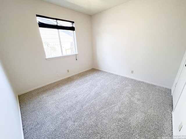 carpeted empty room featuring baseboards