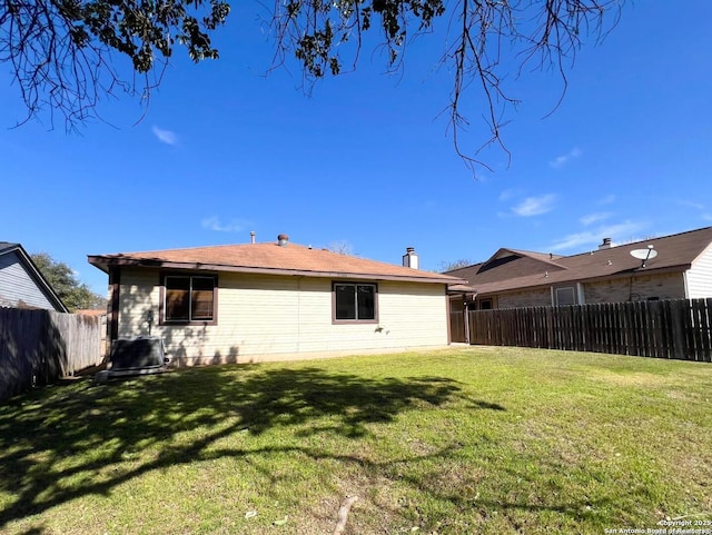 back of house featuring a fenced backyard and a lawn