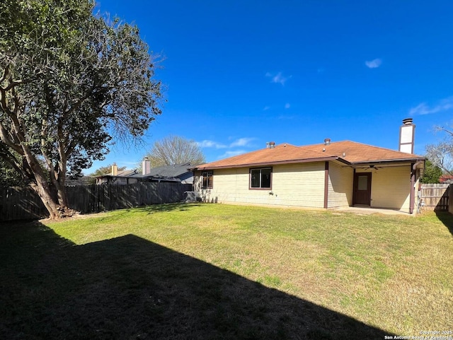 rear view of house with a lawn, a patio, a fenced backyard, ceiling fan, and a chimney